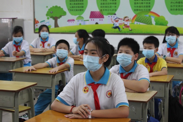 复学第一天,同学们佩戴口罩,认真聆听着《返校学生日常行为规范指引》。.JPG